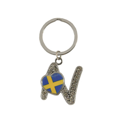 Metallnyckelring med bokstaven N. Bokstaven är dekorerad med glitterstenar. På bokstaven finns även ett hjärta med en svensk flagga.