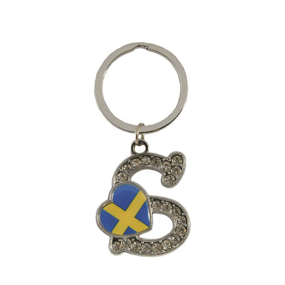 Metallnyckelring med bokstaven S. Bokstaven är dekorerad med glitterstenar. På bokstaven finns även ett hjärta med en svensk flagga.