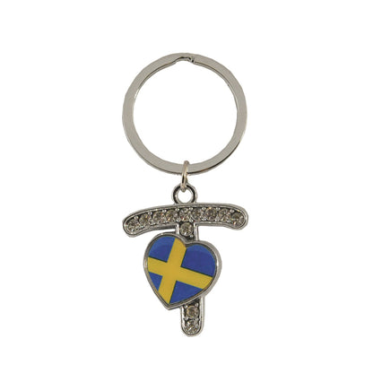 Metallnyckelring med bokstaven T. Bokstaven är dekorerad med glitterstenar. På bokstaven finns även ett hjärta med en svensk flagga.