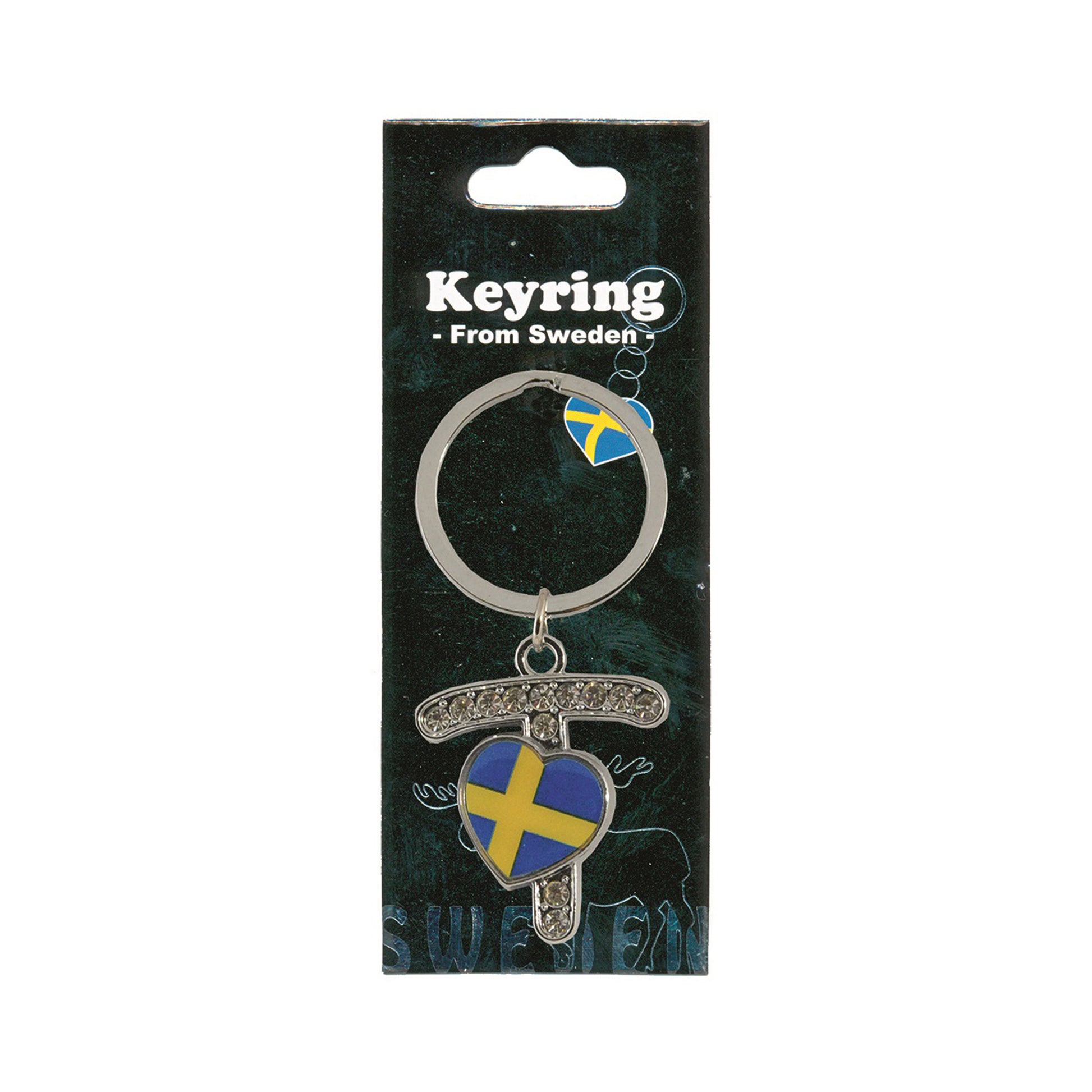 Metallnyckelring med bokstaven T. Bokstaven är dekorerad med glitterstenar. På bokstaven finns även ett hjärta med en svensk flagga. Visas här i sin förpackning. Svart förpackning med  texten "Keyring från Sweden" i vitt.