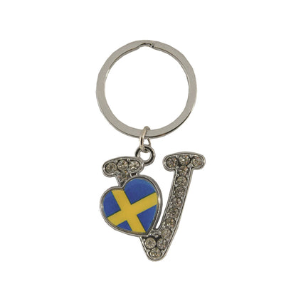 Metallnyckelring med bokstaven V. Bokstaven är dekorerad med glitterstenar. På bokstaven finns även ett hjärta med en svensk flagga.