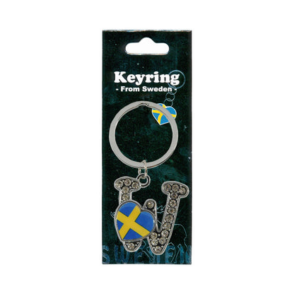 Metallnyckelring med bokstaven W. Bokstaven är dekorerad med glitterstenar. På bokstaven finns även ett hjärta med en svensk flagga. Visas här i sin förpackning. Svart förpackning med  texten "Keyring från Sweden" i vitt.