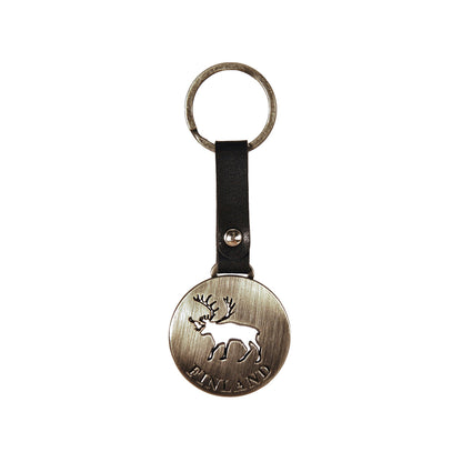 Rund, silverfärgad metallnyckelring med utskuret renmotiv och texten "Finland", med svart läderband.
