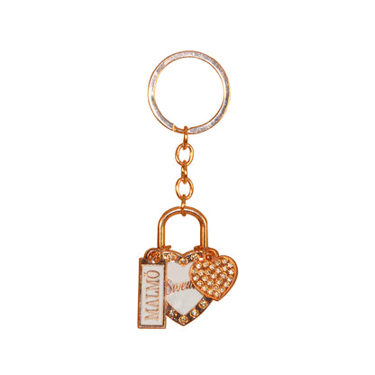 Souvenirnyckelring med två hjärtan – ett större med glittrig roseguldsram, ljusblå mitt och texten Sweden, och ett mindre hjärta prytt med glitterstenar – samt en skylt med texten Malmö.