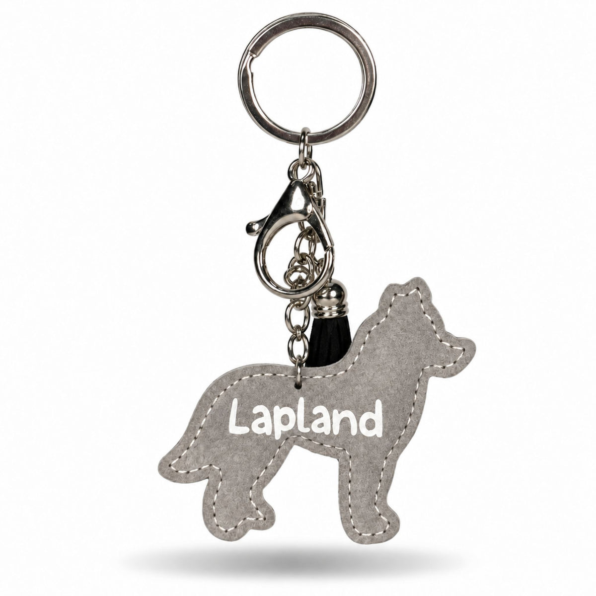 Baksidan av en grå husky formad nyckelring med texten "Lapland". Nyckelringen har en svart tofs samt en silverfärgad karbinhake och ring.