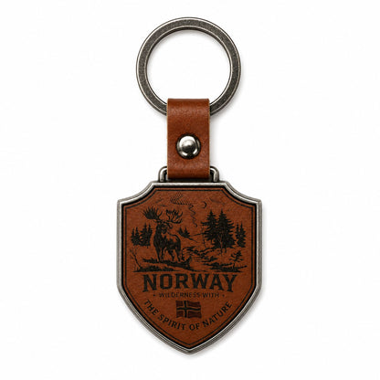 Baksidan av nyckelring i metall som hänger i ett brunt läderband med metallring. Nyckelringen är sköld formad och pryds av älgmotiv, Norge flaggan och texten "Norway Wilderness with the spirit of nature" på brunt läder.