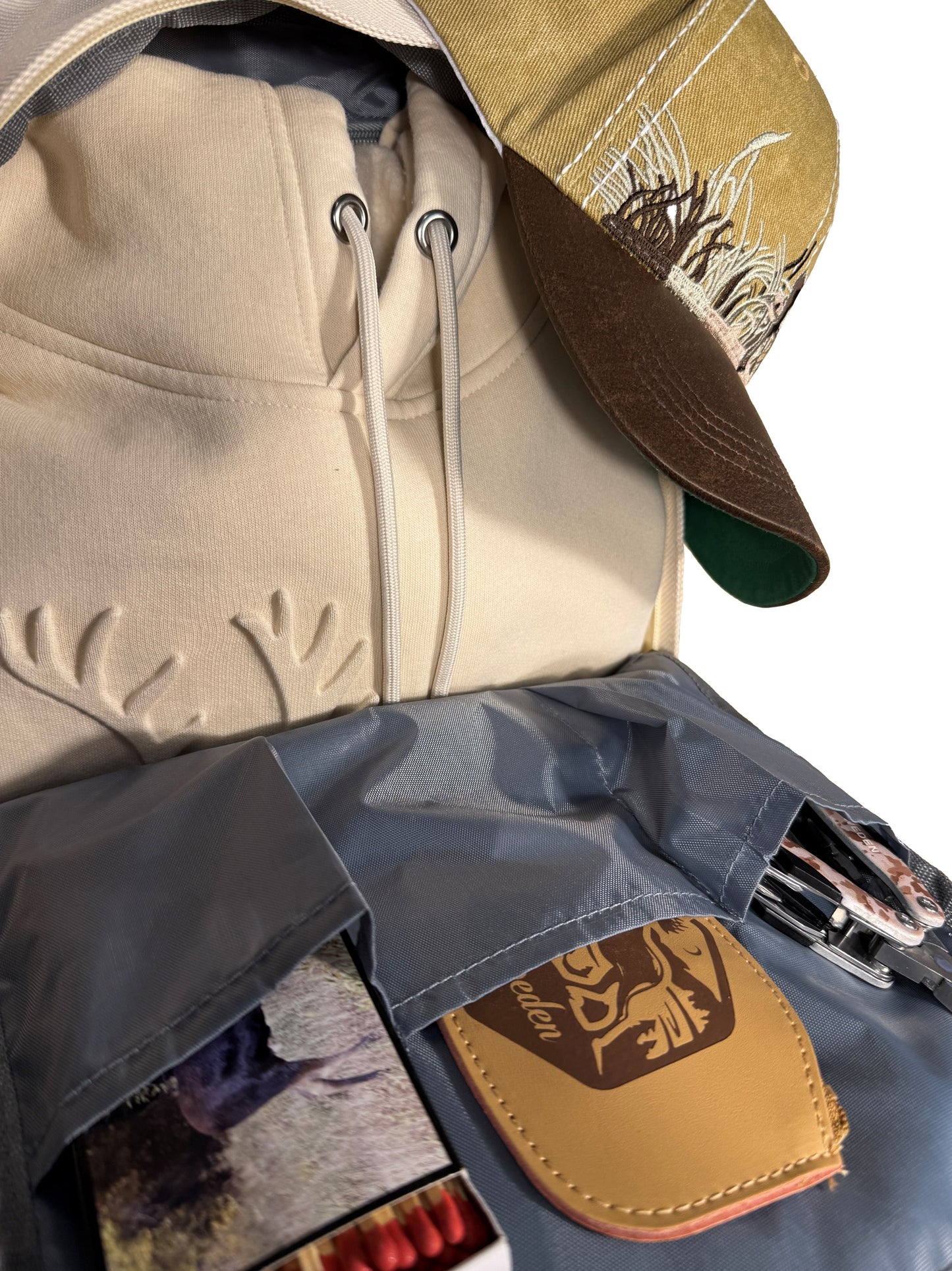 Insidan av beige ryggsäck med 5 olika innerfack. Visas här med produkter i ryggsäcken.