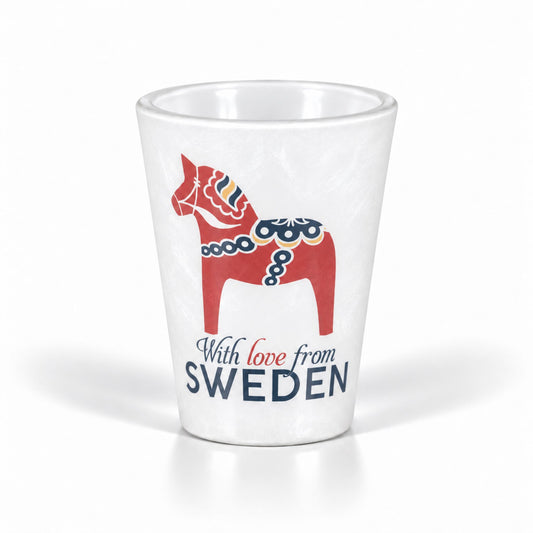 Vitt shotglas med frostig yta som ger illusionen av is, dekorerat med en röd dalahäst och texten "With love from SWEDEN". En festlig souvenir med svensk tradition.