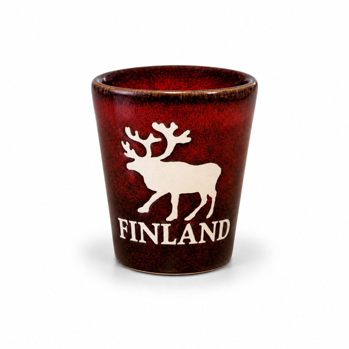 Rustikt rött shotglas med motiv av en ren och texten "Finland", perfekt för snaps eller shots. En festlig souvenir med finsk charm.