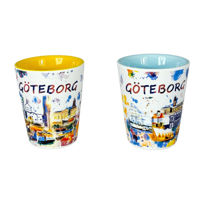 Två shotglas med Göteborgsmotiv – ett med ljusblå insida och ett med gul insida, placerade sida vid sida.