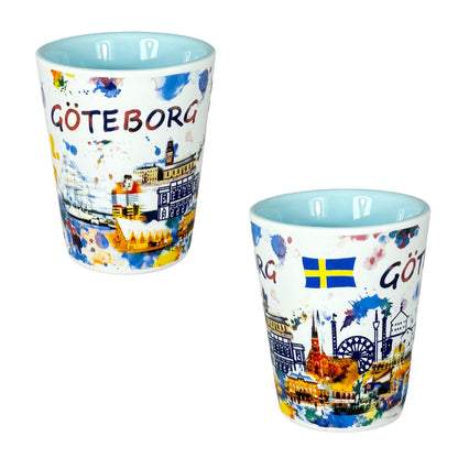 Shotglas med ljusblå insida, visat från två vinklar för att visa hela det färgstarka Göteborgsmotivet.