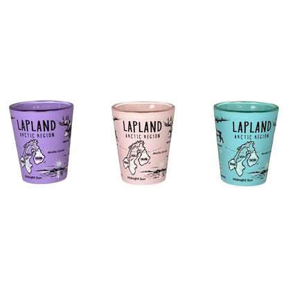 Tre shotglas: ett lila, ett rosa och ett ljusblått med svartvita Lappland-symboler, stående bredvid varandra.

