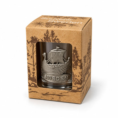 Shotglas med metallmärke föreställande ett vikingskepp och texten "Sweden" i sin förpackning sett snett framifrån.