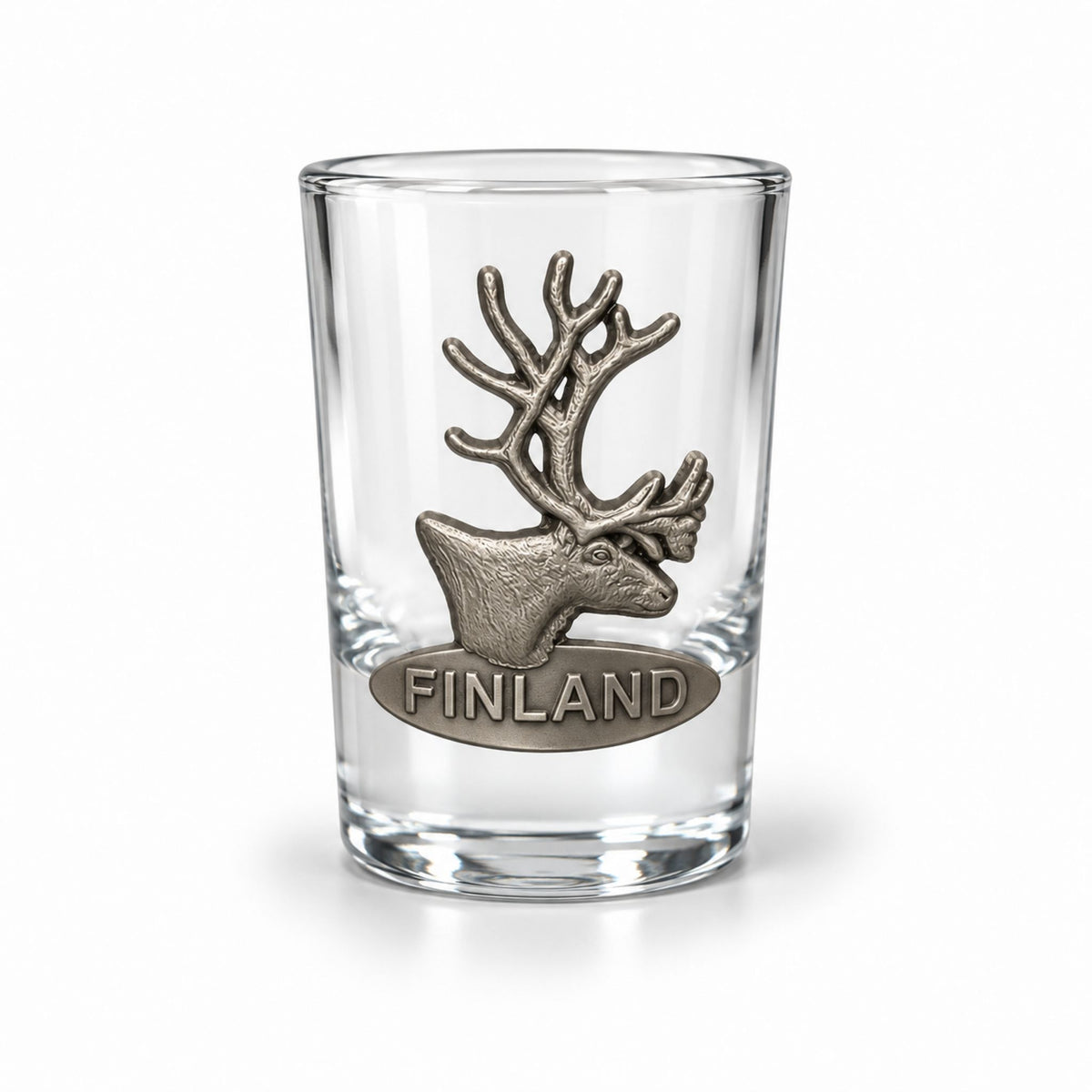 Shotglas prytt med ett metallmärke i form av en ren och texten "Finland".