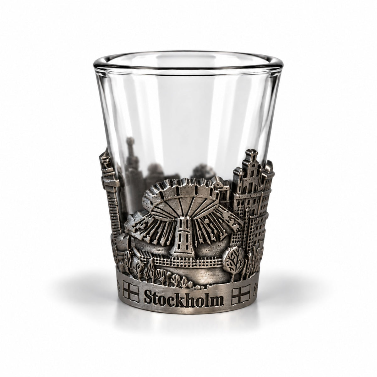 Shotsglas i glas med ett omslag i tennfärgad metall med Stockholmsmotiv och texten Stockholm. 