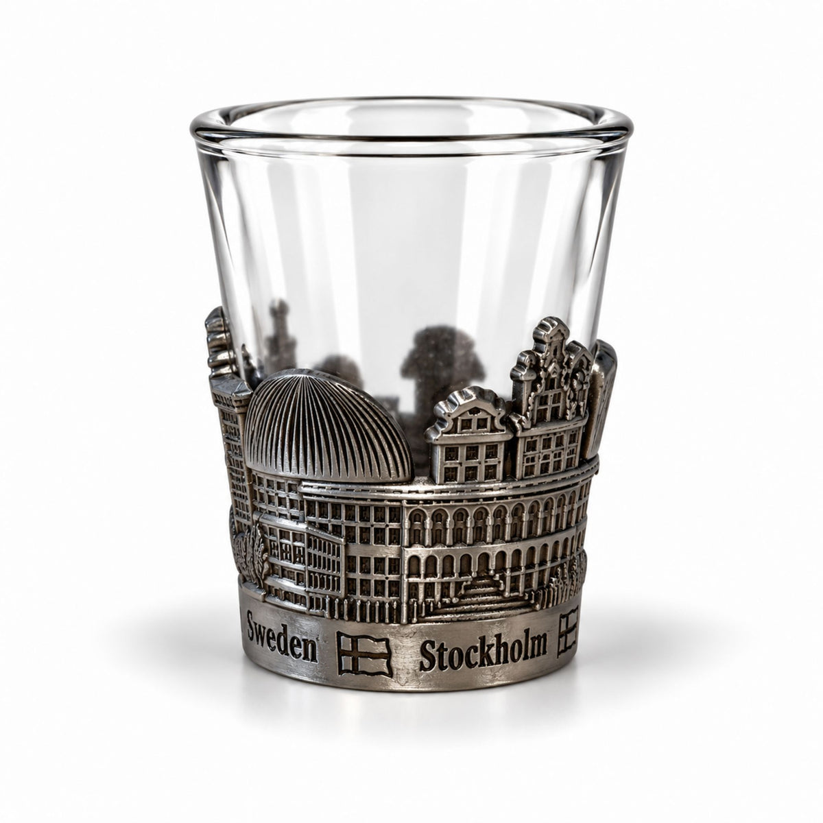 Shotsglas i glas med ett omslag i tennfärgad metall med Stockholmsmotiv och texten Sweden och Stockholm.