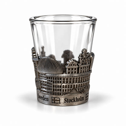 Shotsglas i glas med ett omslag i tennfärgad metall med Stockholmsmotiv och texten Sweden och Stockholm.