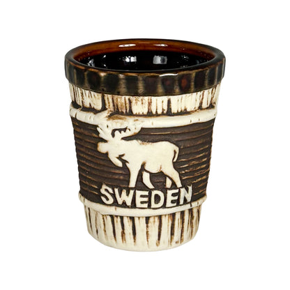 Shotglas med trämönster och älgmotiv samt texten "Sweden" på framsidan.