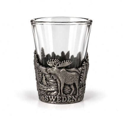 Shotsglas i glas med ett omslag i tennfärgad metall med skogsmotiv, älg och texten Sweden.