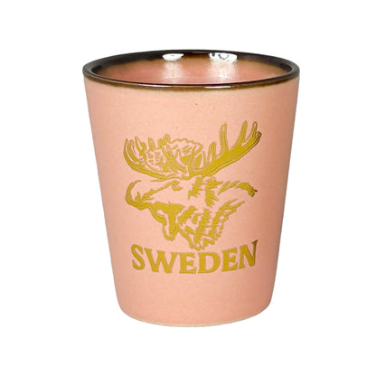 Rosa shotglas med guldfärgat älghuvud och texten "Sweden".