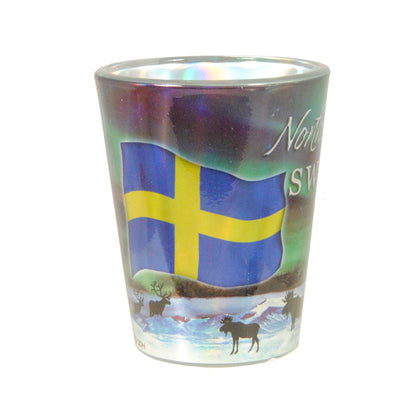 Shotglas med svenska flaggan, norrsken och siluetter av renar och älgar.