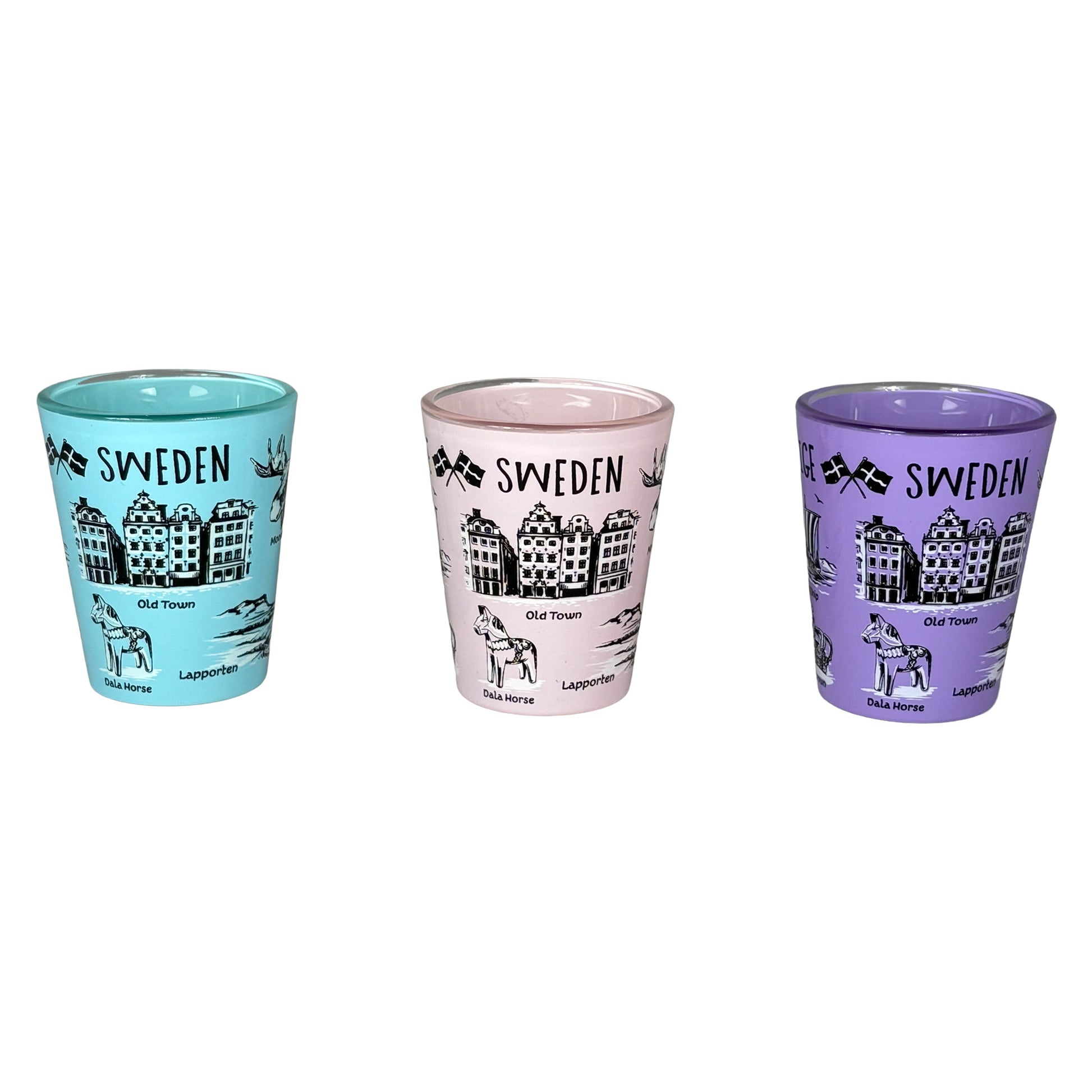 Tre shotglas, ett lila, ett rosa och ett ljusblått med svartvita svenska symboler, stående bredvid varandra.