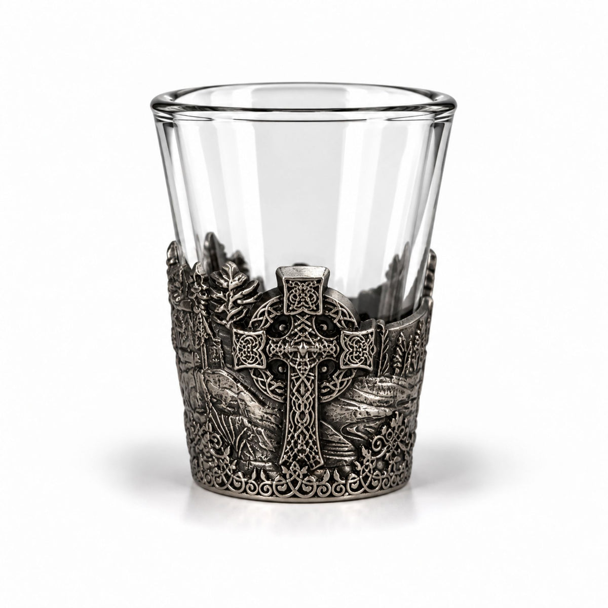 Shotsglas i glas med ett omslag i tennfärgad metall med vikingamotiv. Här syns ett keltiskt kors.