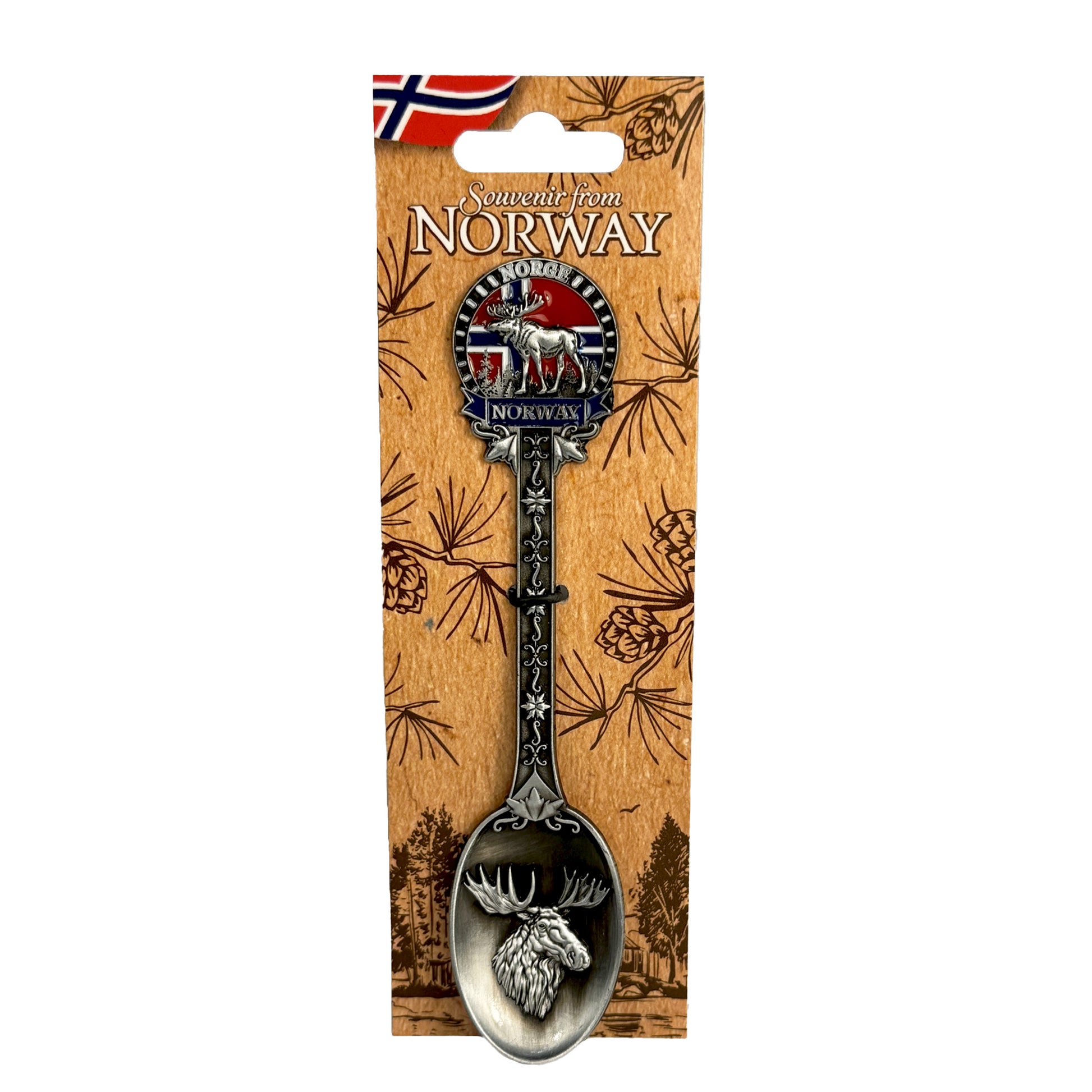 Silverfärgad souvenirsked med ett älghuvud i skedens kupa. Skaftet är dekorerat med ett fint mönster, en älg, norska flaggan samt texten "Norge" och "Norway". Visas här på ljusbrun hängetikett prydd med ett mörkbrunt skogsmotiv, norska flagga och texten "Souvenir from Norway".