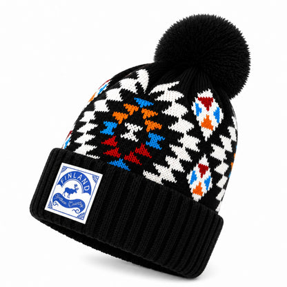Svart stickad mössa med tofs, dekorerad med ett mönster i vitt, blått, rött och orange, samt ett litet märke framtill med texten "Finland Northern Country" - sedd från sidan. 