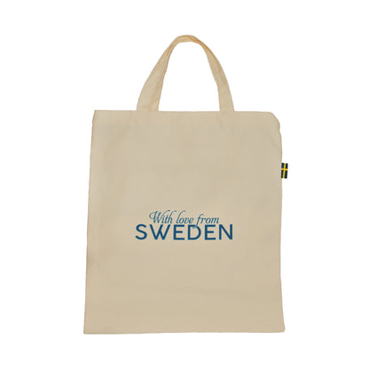 Baksida av tygkasse med texten "With love from SWEDEN" i blått. På höger sida av kassen finns en liten svensk flagga fastsydd. 