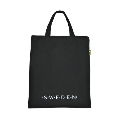 Baksida av svart tygkasse, dekorerad med texten "SWEDEN" och "Sverige" i vitt. 