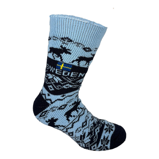 Ljusblå stickad socka med mörkblått älgmönster, texten SWEDEN och liten svensk flagga. Mjuk och mysig med svensk känsla.