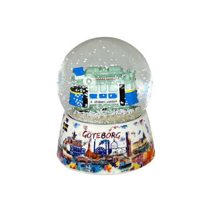 Vattenglob med en klassisk spårvagn från Göteborg inuti, med yrande snöflingor.

