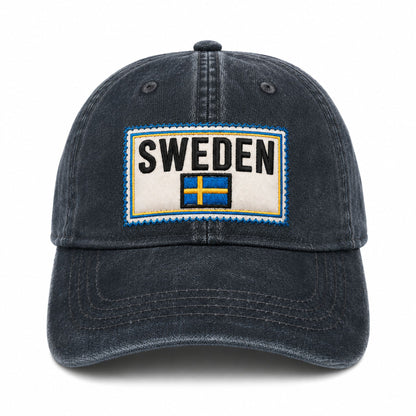 Blå vaxad keps med svensk flagga och texten "SWEDEN". Sedd rakt framifrån.