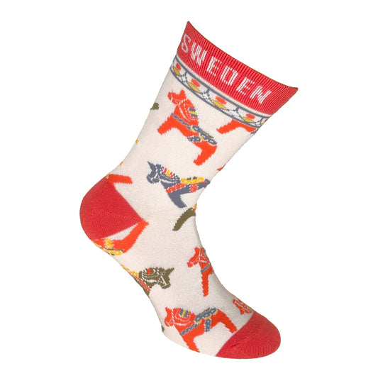 Vit strumpa med röd häl och tå, samt en röd rand högst upp med texten "Sweden". Dekorerad med färgglada dalahästar – en svensk souvenirstrumpa med traditionellt motiv.